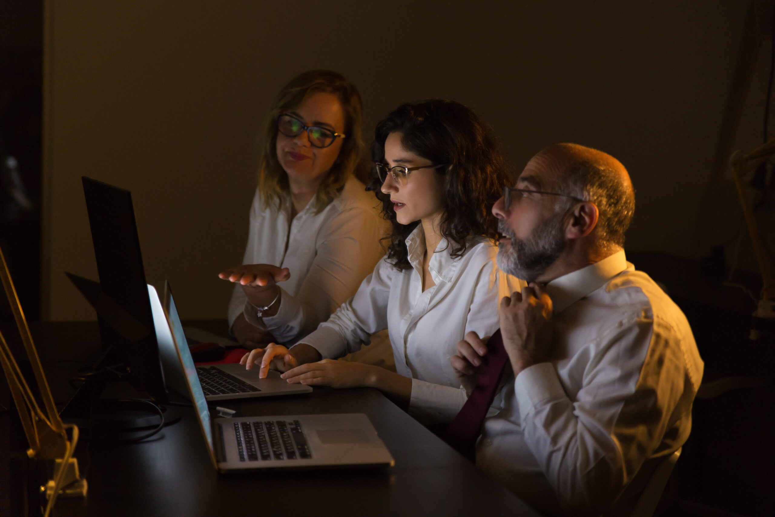 Colleagues discussing work in dark office